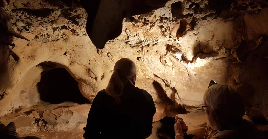 Deux chercheurs examinent les gravures rupestres de la grotte de La Roche-Cotard à la lampe torche, Val de Loire, France