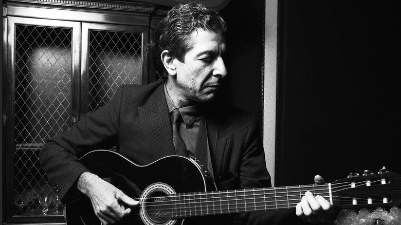 Leonard Cohen jouant de la guitare en costume